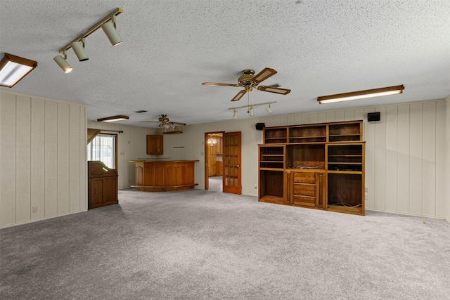4611 Francis Ct, Granbury, TX 76049 - unfurnished living room featuring a ceiling fan, a textured ceiling, track lighting, carpet, and wood walls