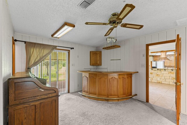 4611 Francis Ct, Granbury, TX 76049 - kitchen featuring ceiling fan, light carpet, brown cabinetry, white refrigerator with ice dispenser, and a textured ceiling