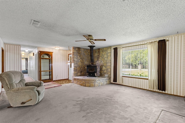 4611 Francis Ct, Granbury, TX 76049 - unfurnished living room featuring wallpapered walls, a wood stove, a textured ceiling, ceiling fan, and carpet floors