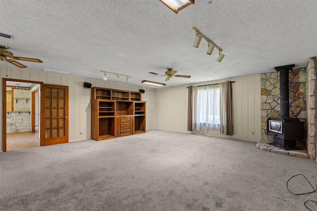 4611 Francis Ct, Granbury, TX 76049 - unfurnished living room featuring ceiling fan, a wood stove, track lighting, a textured ceiling, and carpet