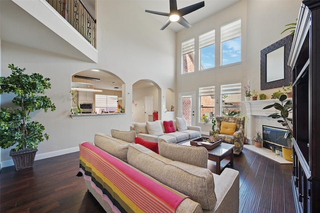 14766 Daneway Dr, Frisco, TX 75035 - living area with ceiling fan, arched walkways, a high ceiling, baseboards, and dark wood-style flooring