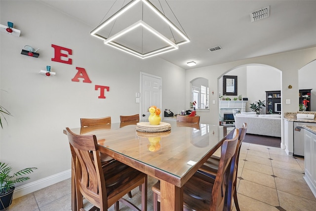 14766 Daneway Dr, Frisco, TX 75035 - dining area featuring light tile patterned flooring, arched walkways, a fireplace, and baseboards