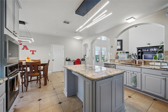 14766 Daneway Dr, Frisco, TX 75035 - kitchen featuring a sink, appliances with stainless steel finishes, gray cabinets, a kitchen island, and arched walkways