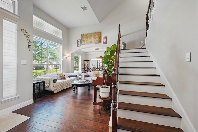 14766 Daneway Dr, Frisco, TX 75035 - staircase featuring a towering ceiling, wood-type flooring, arched walkways, and baseboards
