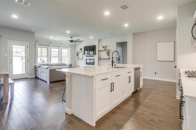 kitchen with a sink, stainless steel appliances, open floor plan, light countertops, and white cabinets
