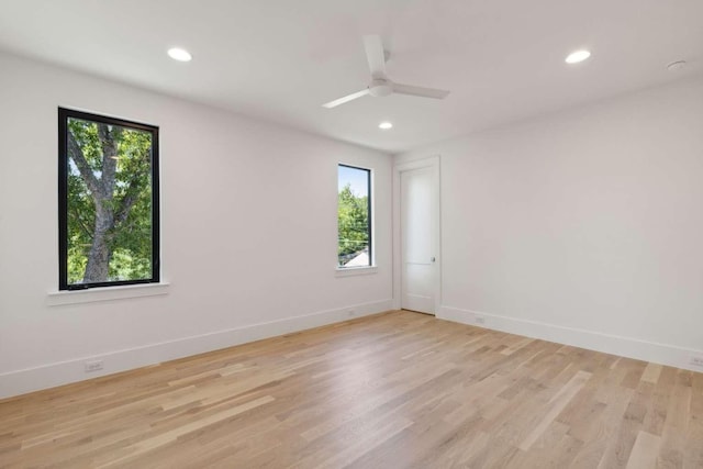 spare room with plenty of natural light, recessed lighting, light wood-style flooring, baseboards, and ceiling fan