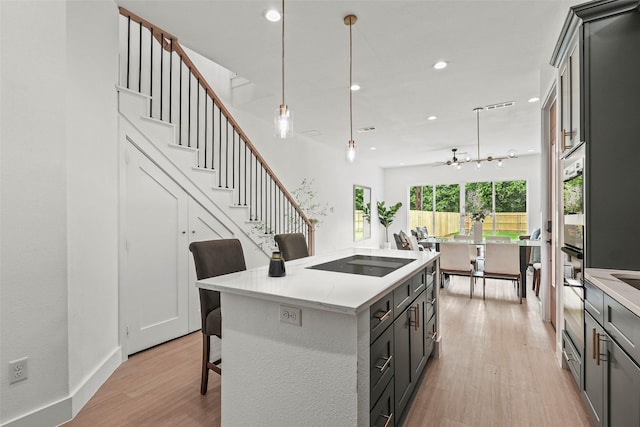 2522 Jeffries St, Dallas, TX 75215 - kitchen with black electric stovetop, light wood finished floors, a breakfast bar area, recessed lighting, and light countertops