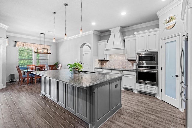 726 County Road 3355, Paradise, TX 76073 - kitchen featuring appliances with stainless steel finishes, custom exhaust hood, white cabinetry, arched walkways, and tasteful backsplash