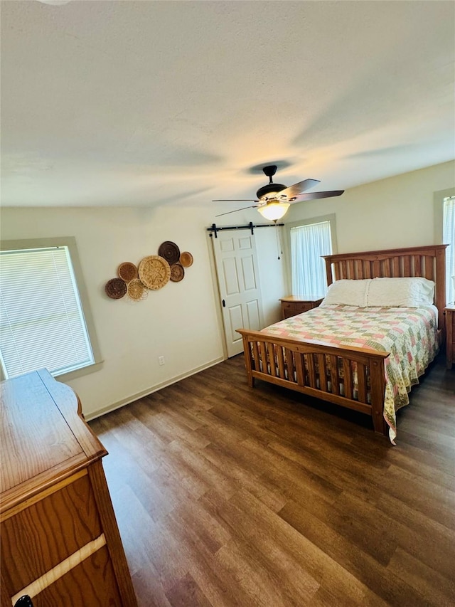 900 Boyd Ave, Lindale, TX 75701 - bedroom with wood finished floors, a barn door, baseboards, and a ceiling fan
