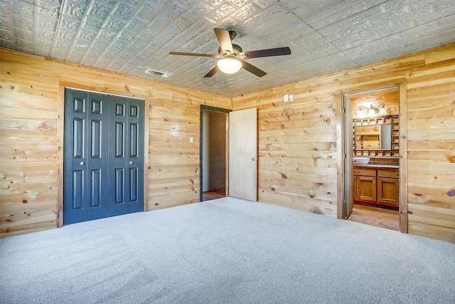 5101 County Road 1205, Cleburne, TX 76031 - bedroom featuring wood walls, carpet flooring, connected bathroom, ceiling fan, and multiple closets