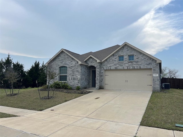 409 Petty Way, Fate, TX 75189 - view of front of house featuring central air condition unit, driveway, a garage, brick siding, and stone siding