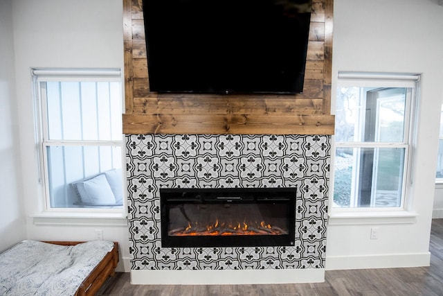 100 E 3rd St, Tolar, TX 76476 - detailed view of a tile fireplace, wood finished floors, and baseboards