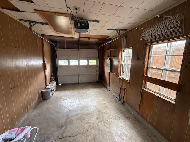 garage with a garage door opener and wood walls
