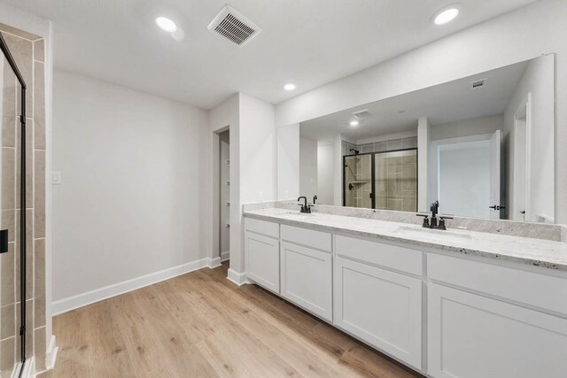 736 Carson Ln, Pilot Point, TX 76258 - bathroom featuring a stall shower, wood finished floors, baseboards, double vanity, and recessed lighting