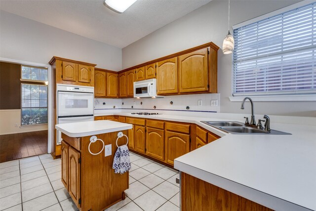1729 Sheffield Dr, Garland, TX 75040 - kitchen with a sink, white appliances, light countertops, a center island, and brown cabinetry