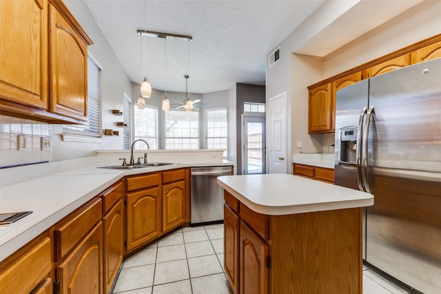 1729 Sheffield Dr, Garland, TX 75040 - kitchen with stainless steel appliances, light countertops, brown cabinetry, a textured ceiling, and hanging light fixtures