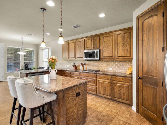 214 Crestbrook Dr, Rockwall, TX 75087 - kitchen featuring appliances with stainless steel finishes, tasteful backsplash, brown cabinets, recessed lighting, and a kitchen breakfast bar
