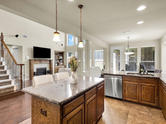 214 Crestbrook Dr, Rockwall, TX 75087 - kitchen featuring stainless steel dishwasher, a sink, a tile fireplace, open floor plan, and a center island