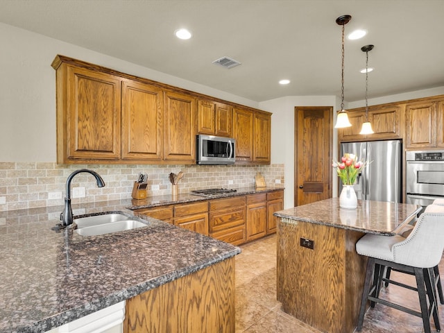 214 Crestbrook Dr, Rockwall, TX 75087 - kitchen featuring appliances with stainless steel finishes, a sink, brown cabinets, backsplash, and a center island