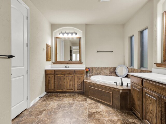 214 Crestbrook Dr, Rockwall, TX 75087 - full bathroom with two vanities, a garden tub, and stone finish floors