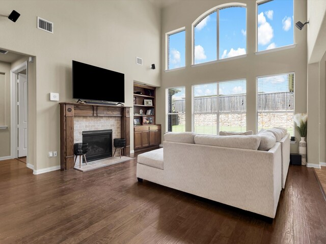 214 Crestbrook Dr, Rockwall, TX 75087 - living area with a high ceiling, a fireplace with flush hearth, dark wood-style flooring, baseboards, and built in shelves