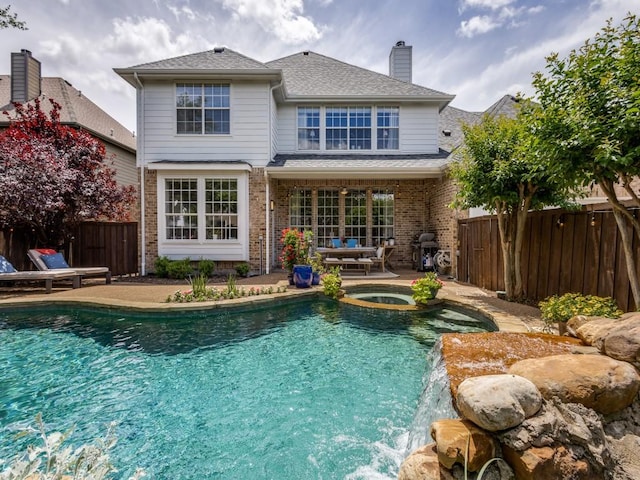 5040 Loma Alta Dr, Frisco, TX 75034 - back of house with a chimney, brick siding, a fenced backyard, a patio, and a pool with connected hot tub