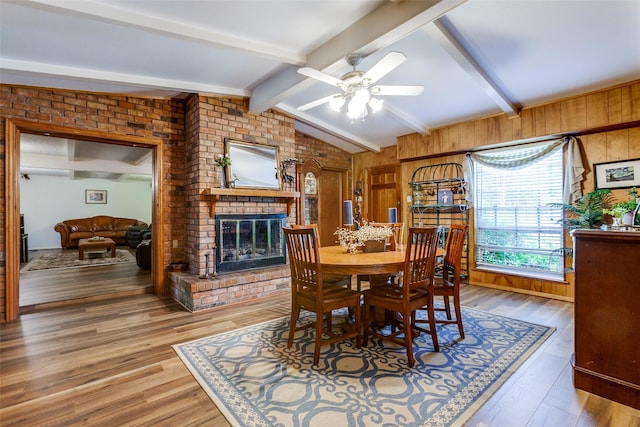 9551 E Lake Highlands Dr, Dallas, TX 75218 - dining space featuring a fireplace, light wood finished floors, a ceiling fan, and wooden walls