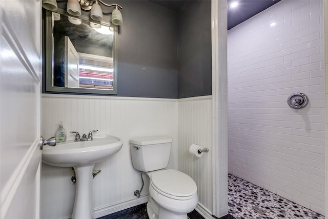 9551 E Lake Highlands Dr, Dallas, TX 75218 - bathroom with toilet, tiled shower, a wainscoted wall, and a sink