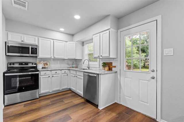 kitchen with stainless steel appliances, a sink, dark wood-style floors, white cabinetry, and recessed lighting