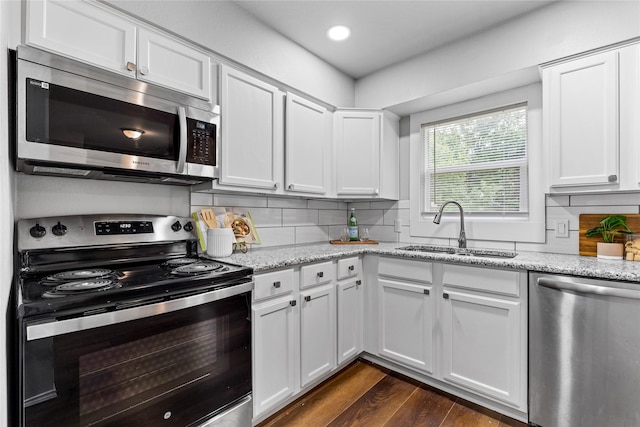 kitchen featuring stainless steel appliances, a sink, white cabinets, backsplash, and dark wood-type flooring