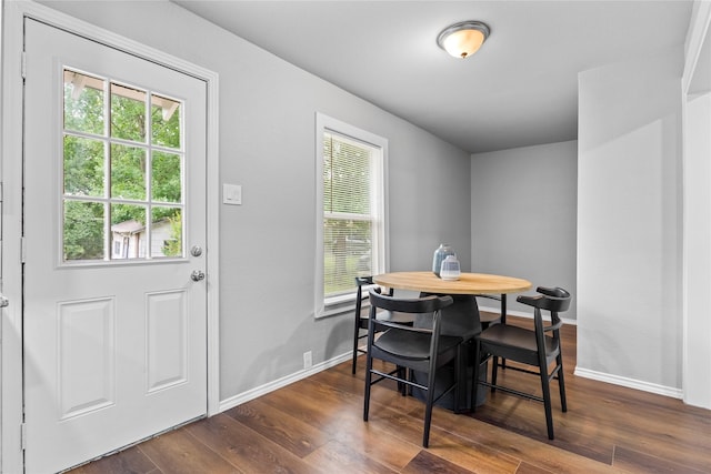 dining space featuring healthy amount of natural light, dark wood-style floors, and baseboards
