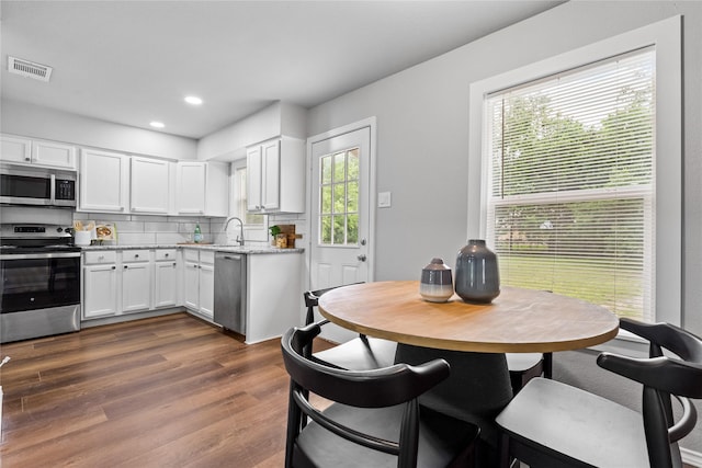 kitchen with appliances with stainless steel finishes, white cabinets, decorative backsplash, dark wood-type flooring, and recessed lighting