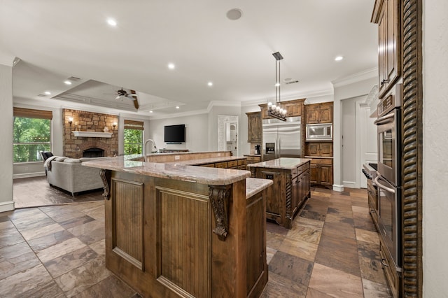 113 Welford Ln, Southlake, TX 76092 - kitchen with built in appliances, a large island with sink, a stone fireplace, ornamental molding, and open floor plan