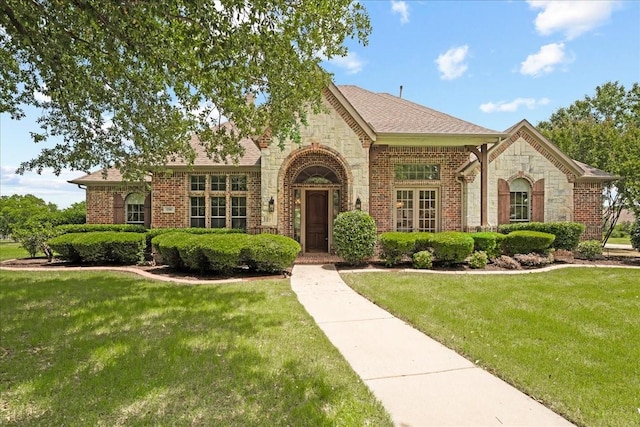 1740 Highland Meadows Dr, Prosper, TX 75078 - view of front facade with stone siding, a front lawn, brick siding, and a shingled roof
