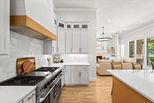 1740 Highland Meadows Dr, Prosper, TX 75078 - kitchen with double oven range, ornamental molding, premium range hood, light wood-type flooring, and a stone fireplace