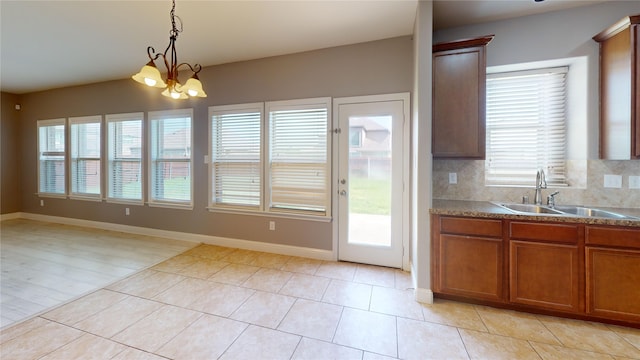 3114 Flowering Springs Dr, Forney, TX 75126 - kitchen featuring a sink, brown cabinetry, light tile patterned floors, hanging light fixtures, and baseboards