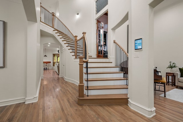 608 King Ranch Rd, Southlake, TX 76092 - stairway with arched walkways, a towering ceiling, wood finished floors, and baseboards