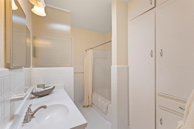 10209 Solta Dr, Dallas, TX 75218 - bathroom with vanity, shower / tub combo with curtain, tile walls, and a wainscoted wall