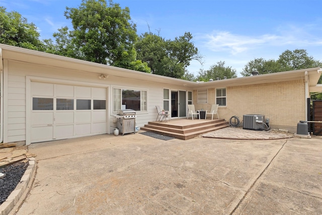 10209 Solta Dr, Dallas, TX 75218 - rear view of house featuring a garage, a deck, central AC unit, brick siding, and concrete driveway