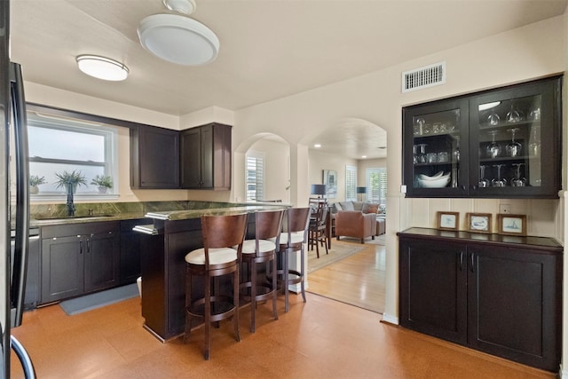 10209 Solta Dr, Dallas, TX 75218 - kitchen with arched walkways, light floors, a kitchen bar, a sink, and open floor plan