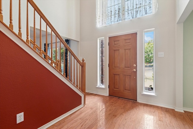 entrance foyer with wood finished floors, baseboards, stairs, and a high ceiling