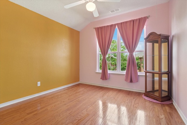 spare room featuring wood finished floors, a ceiling fan, baseboards, and vaulted ceiling