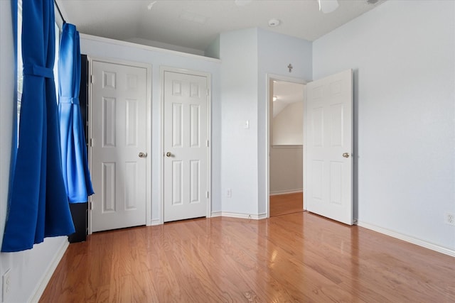 unfurnished bedroom featuring wood finished floors, baseboards, and ceiling fan