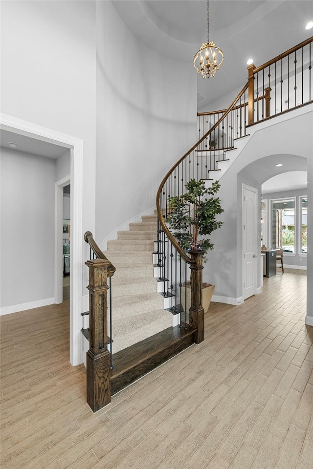 4530 Crossvine Dr, Prosper, TX 75078 - stairway with wood finished floors, arched walkways, a high ceiling, baseboards, and a chandelier