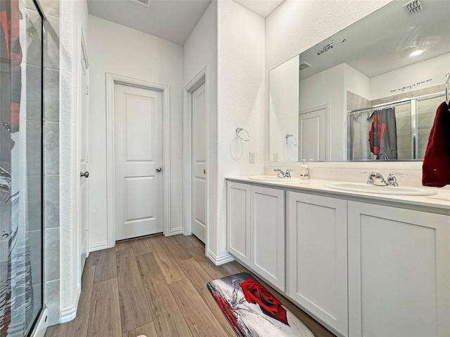 8309 Caracara Dr, Mckinney, TX 75071 - full bathroom featuring a stall shower, wood finished floors, double vanity, and a textured wall