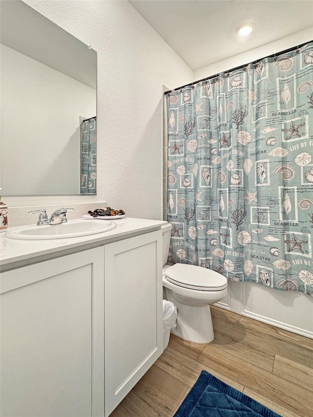 8309 Caracara Dr, Mckinney, TX 75071 - full bathroom with wood finished floors, toilet, vanity, curtained shower, and a textured wall