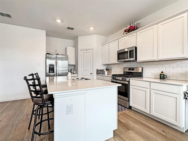 8309 Caracara Dr, Mckinney, TX 75071 - kitchen with appliances with stainless steel finishes, light wood-type flooring, a breakfast bar area, backsplash, and recessed lighting
