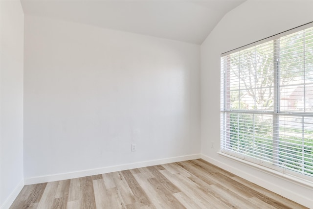 unfurnished room with vaulted ceiling, light wood-style floors, and baseboards