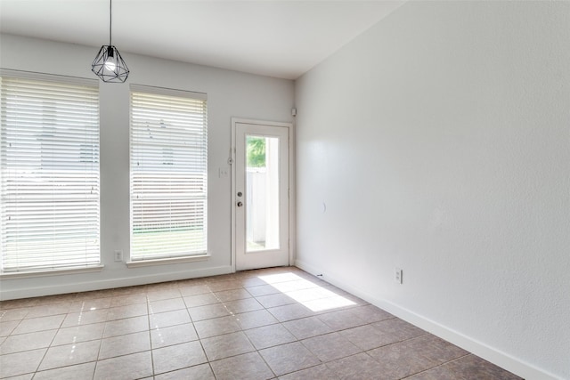 unfurnished dining area with light tile patterned floors and baseboards