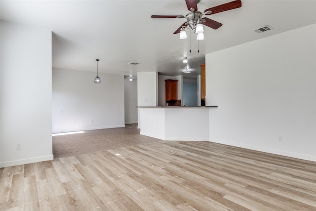 unfurnished living room with a ceiling fan, light wood-style floors, and baseboards